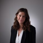 donna con blazer nero e camicia bianca, indossa una collana con ciondolo