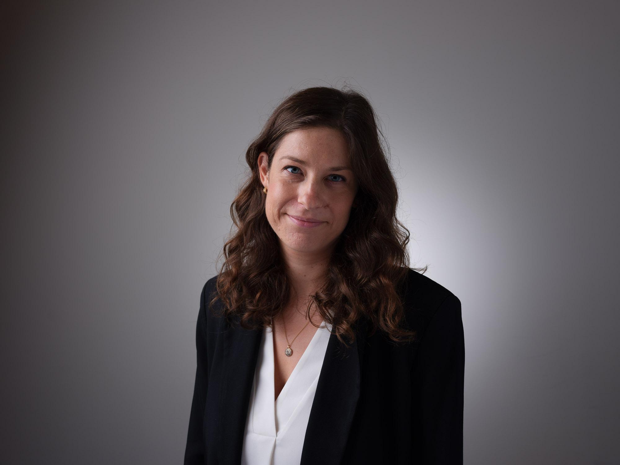 donna con blazer nero e camicia bianca, indossa una collana con ciondolo