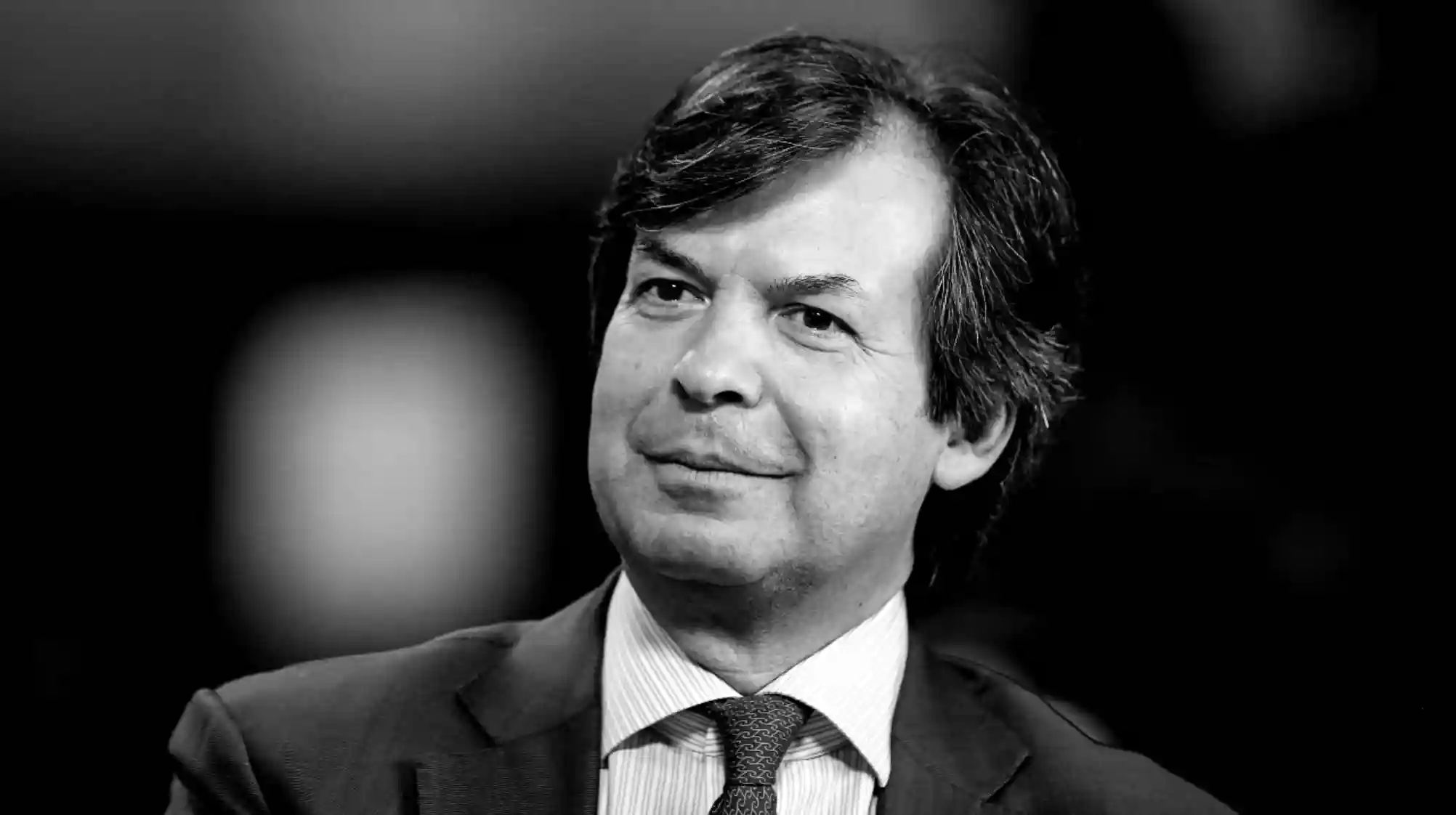 Ritratto in bianco e nero di un uomo in giacca e cravatta, con capelli scuri pettinati di lato.